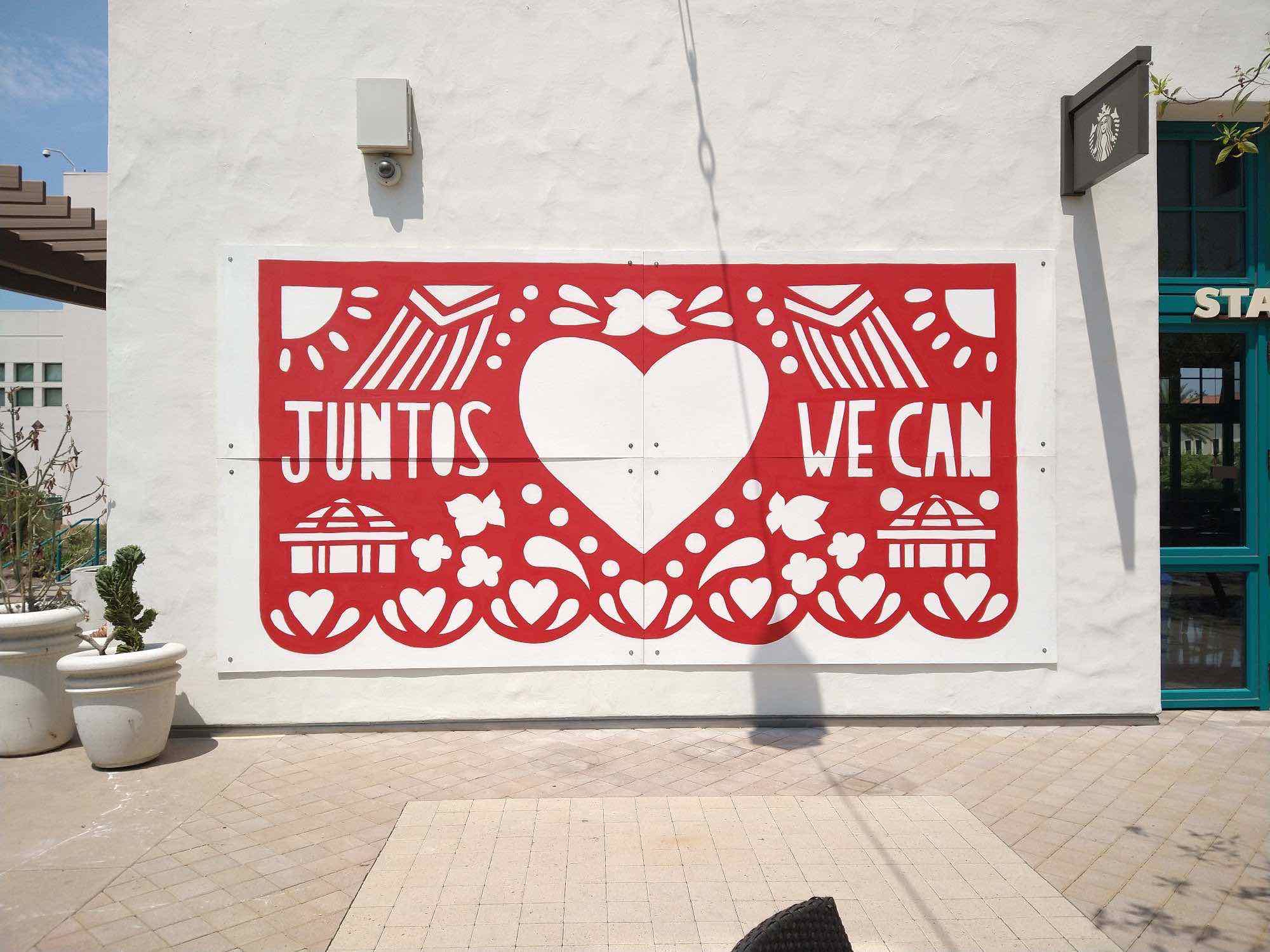 JUNTOS WE CAN, 2021  Enamel paint and plywood  The Division of Student Affairs and Campus Diversity, the School of Art and Design, and Arts Alive SDSU hosted a Social Justice Mural Competition during the worldwide COVID-19 pandemic. During a time of intense turmoil throughout the world, these groups had the goal to “Foster and sustain an environment where all students, faculty, staff, and alumni feel welcomed, supported, and valued by the university.”&nbsp;Itzel Ortuño, an alumnus of SDSU's School of Art and Design, saught to support the university's social justice goals through her art. Inspired by the diversity on campus, Ortuño focused on the celebratory nature of biculturalism on campus and in San Diego.&nbsp;The artist would like to extend her sincerest thanks to Sabrina Davidson, Emily Fox, Yesenia Hayes, Kasie Murdock, Omar Ortuño, Marina Ortuño, and Johnny Villamar for the immense help in making this mural come to life.  itzelortuno.com