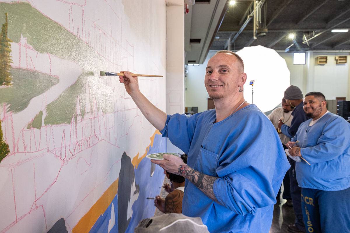 Prison Arts Collective student works on mural at Pelican Bay State Prison as part of a collaborative arts workshop, facilitated by the Cal Poly Humboldt chapter of PAC. Photo courtesy of Peter Merts, 2024..